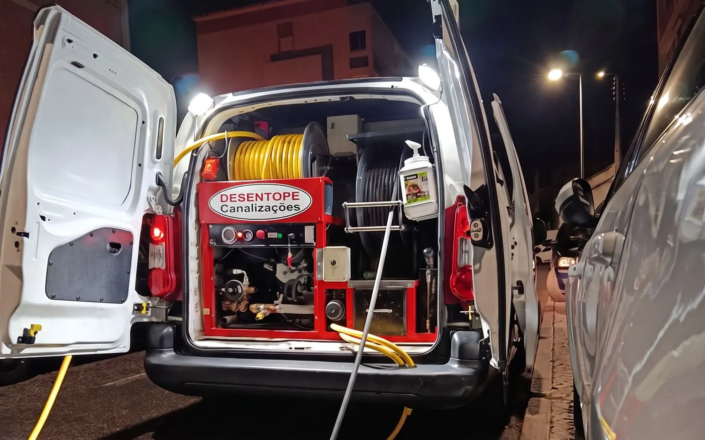 Carrinha de intervenção Desentope aberta à noite, com máquina de alta pressão vermelha e enroladores de mangueira