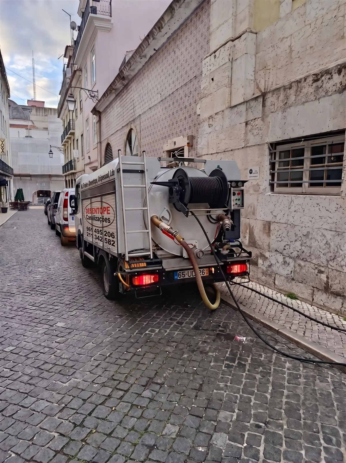 Camião Desentope a desentupir esgoto numa rua empedrada de Lisboa